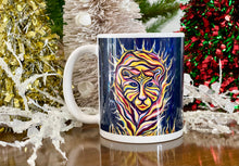 Load image into Gallery viewer, Picture depicts a mug with an image of an abstract tiger with flames around it. The mug is colorful. It is staged on a wooden surface with holiday decorations in the back

